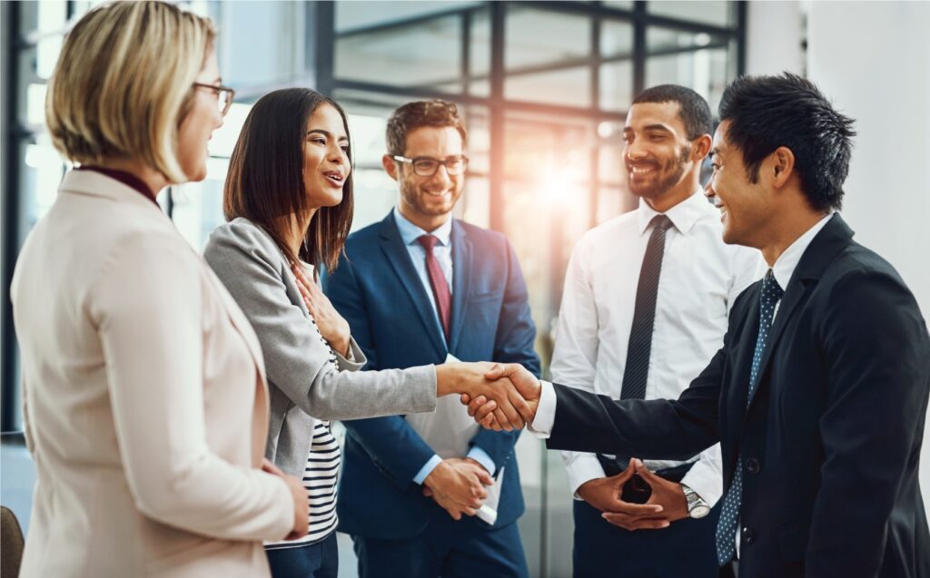 Business men and women shaking hands n an office setting